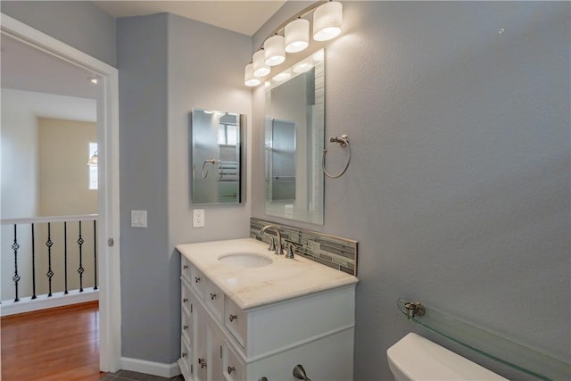 bathroom featuring toilet, decorative backsplash, and vanity