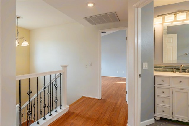 hallway featuring a chandelier, wood-type flooring, and sink