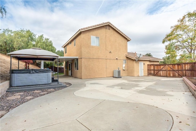 back of property with a patio area, a hot tub, and central air condition unit