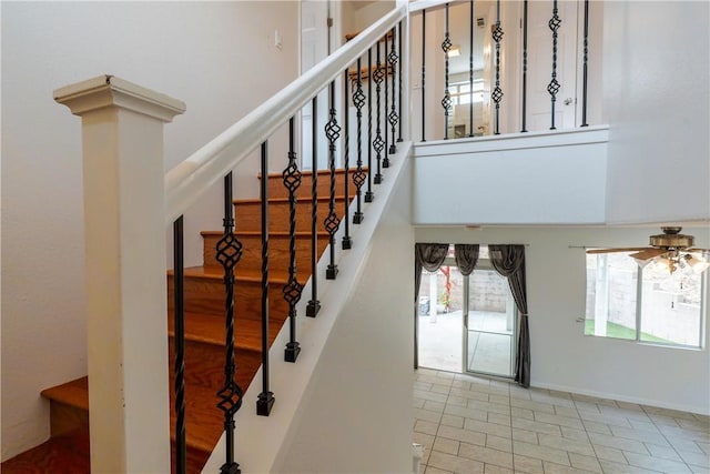 staircase with ceiling fan and tile patterned flooring