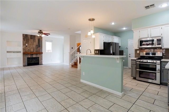 kitchen with white cabinetry, ceiling fan, stainless steel appliances, a kitchen island, and pendant lighting