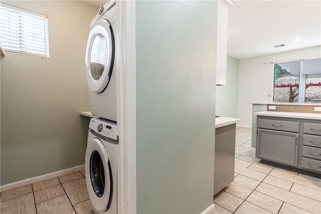 laundry room featuring stacked washer and dryer and light tile patterned flooring