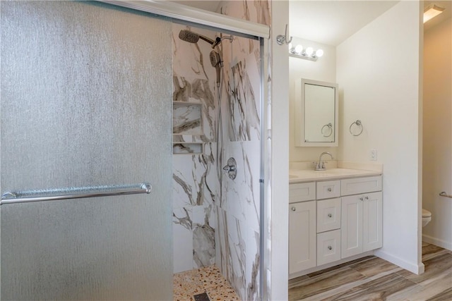 bathroom with hardwood / wood-style flooring, toilet, walk in shower, and vanity