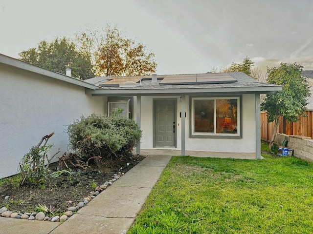 view of exterior entry featuring a yard and solar panels