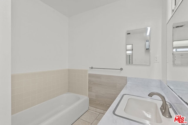 bathroom featuring tile patterned flooring, a tub to relax in, and vanity