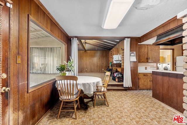 dining area with vaulted ceiling with beams, washer and dryer, and wood walls