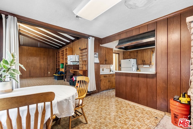 dining space with wood walls and lofted ceiling with beams