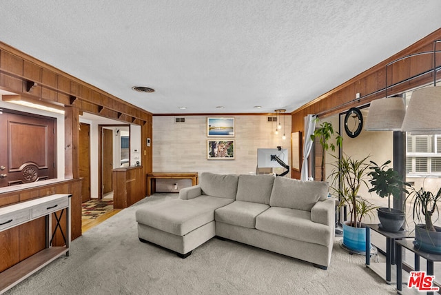 living room featuring light carpet, a textured ceiling, and wood walls