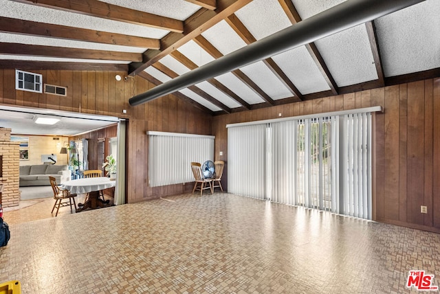 living room featuring wood walls and vaulted ceiling with beams