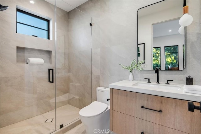 bathroom with a shower with shower door, tile walls, toilet, and vanity