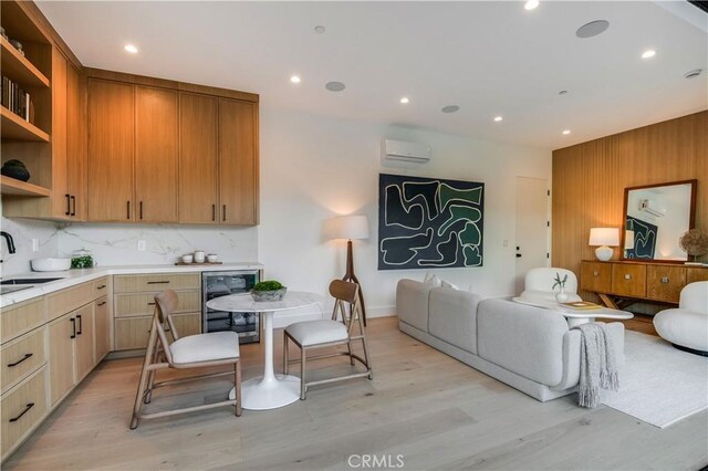 kitchen with a wall mounted AC, backsplash, wine cooler, light hardwood / wood-style flooring, and sink