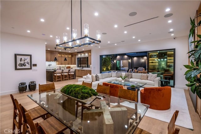 dining area featuring light wood-type flooring, sink, and a chandelier