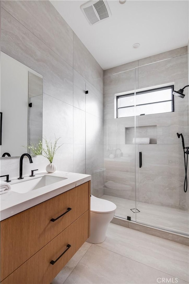 bathroom with a shower with door, tile patterned floors, vanity, and toilet