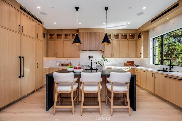 kitchen featuring light brown cabinetry, sink, a kitchen island with sink, and light hardwood / wood-style floors