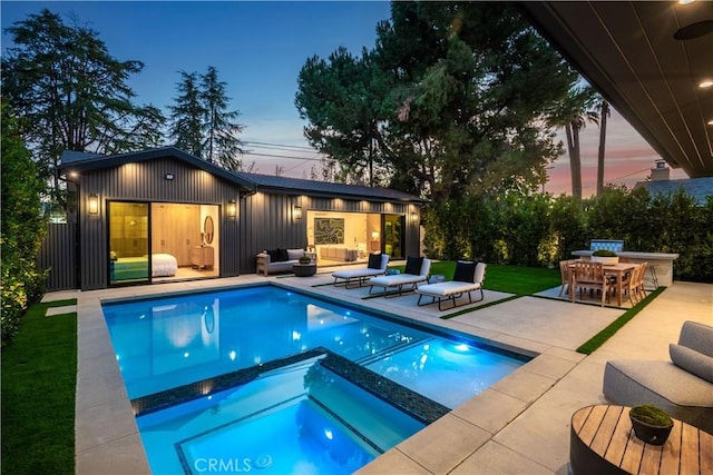 pool at dusk with an outdoor living space, a patio, and an in ground hot tub