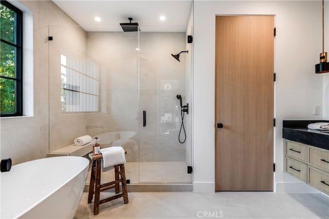 bathroom featuring plus walk in shower, a healthy amount of sunlight, and vanity