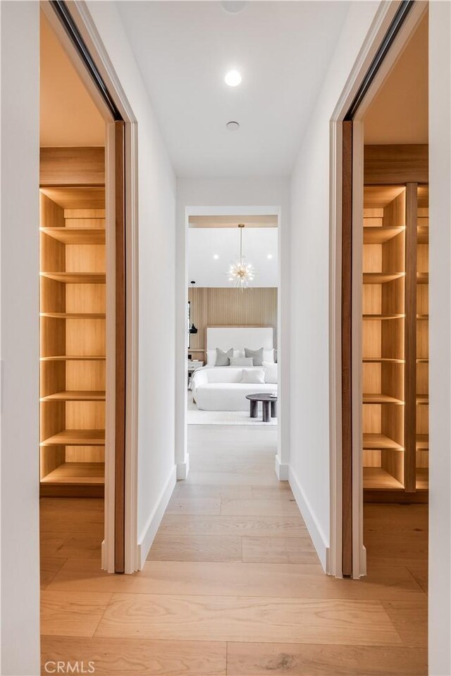 hallway with hardwood / wood-style flooring and a notable chandelier