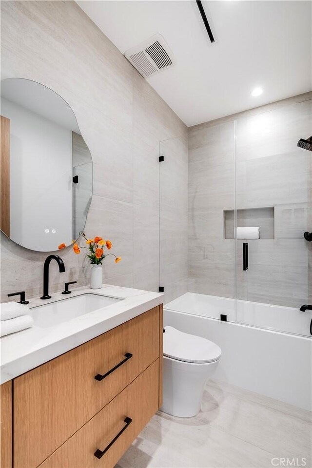 full bathroom with toilet, vanity, tile walls, and shower / washtub combination