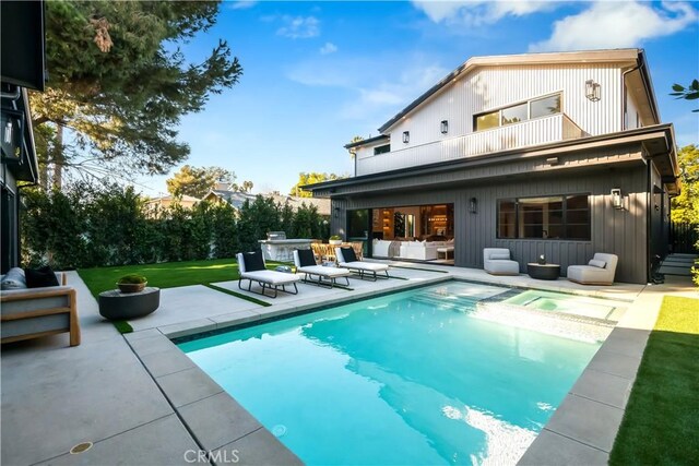 rear view of property featuring a swimming pool with hot tub, a lawn, a patio area, a balcony, and area for grilling