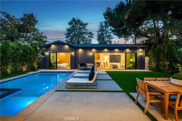 back house at dusk featuring a yard and a patio