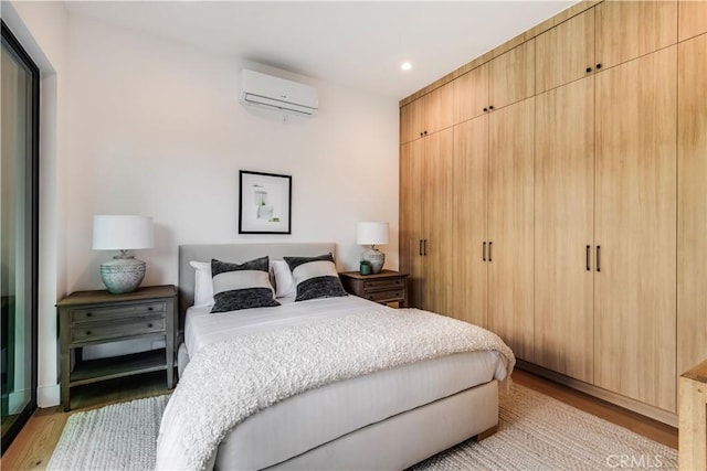 bedroom with light hardwood / wood-style floors, a closet, and a wall unit AC