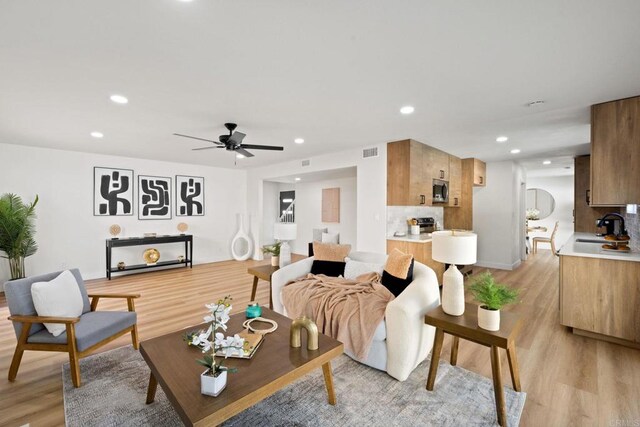 living room with sink, ceiling fan, and light hardwood / wood-style flooring