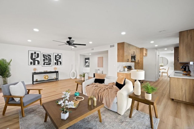 living room with light hardwood / wood-style floors, sink, and ceiling fan