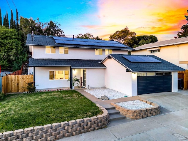 view of front of house featuring a lawn, solar panels, and a garage