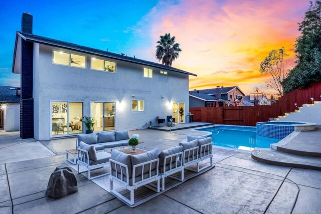 pool at dusk featuring a patio, an outdoor hangout area, and an in ground hot tub