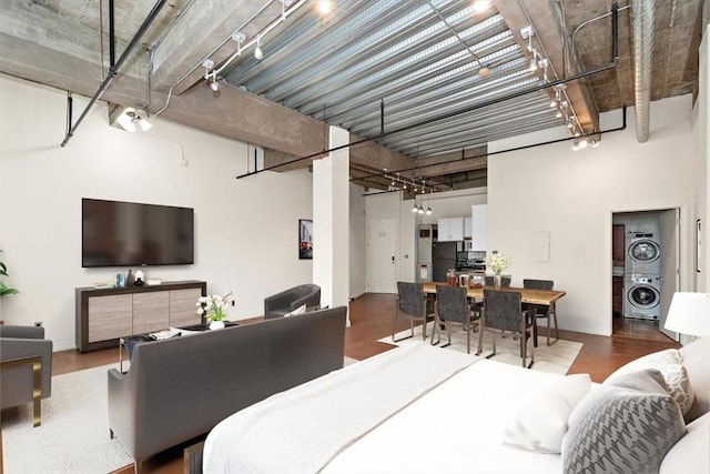 bedroom with a high ceiling, stacked washer / dryer, and rail lighting