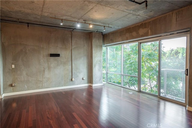 unfurnished room featuring rail lighting, plenty of natural light, and hardwood / wood-style floors