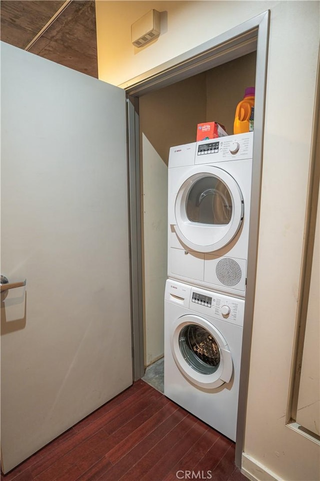 clothes washing area featuring dark hardwood / wood-style flooring and stacked washing maching and dryer