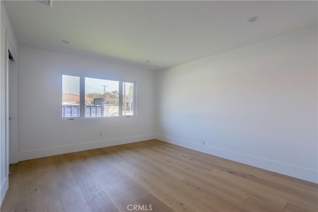 spare room featuring light wood-style floors and baseboards