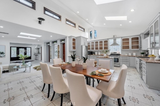 dining area featuring a skylight, plenty of natural light, sink, and a towering ceiling