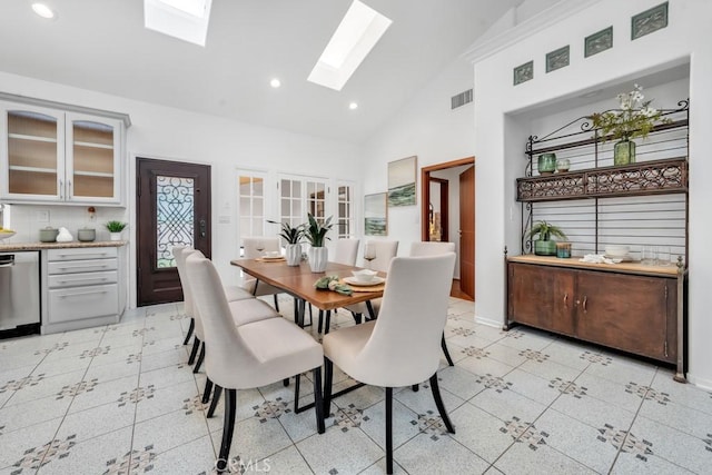 dining space with high vaulted ceiling and a skylight