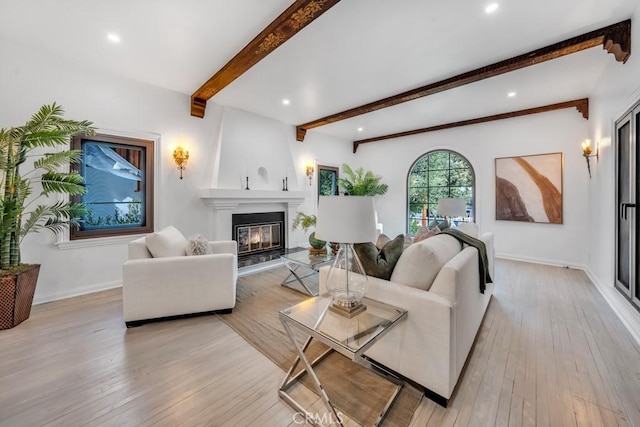 living room featuring a fireplace, beamed ceiling, and light wood-type flooring