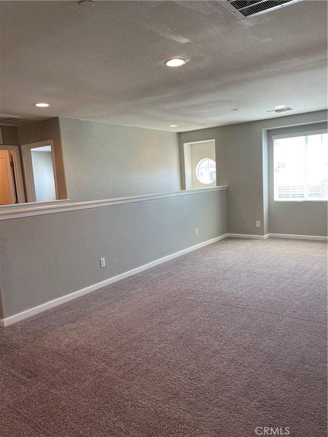 unfurnished room featuring a textured ceiling and carpet flooring