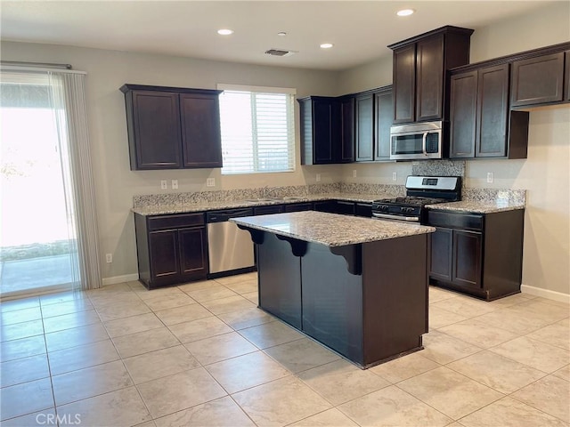 kitchen featuring light tile patterned floors, stainless steel appliances, a wealth of natural light, and a center island