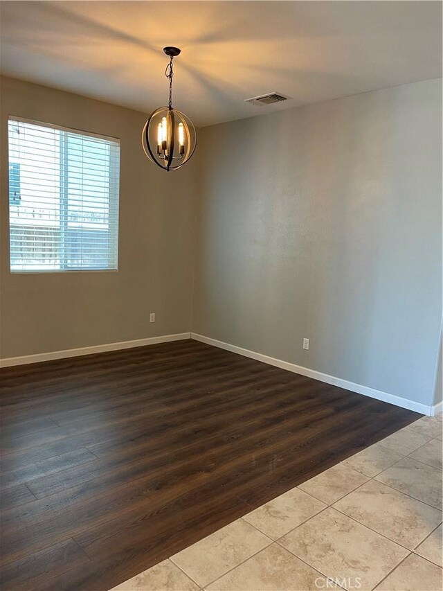 unfurnished room featuring tile patterned floors and an inviting chandelier