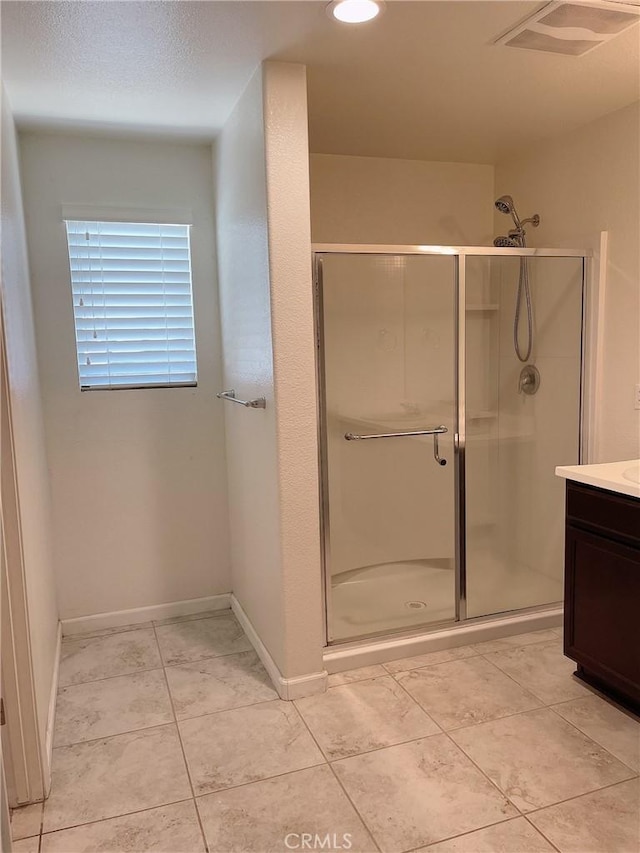 bathroom featuring a shower with door, tile patterned floors, and vanity