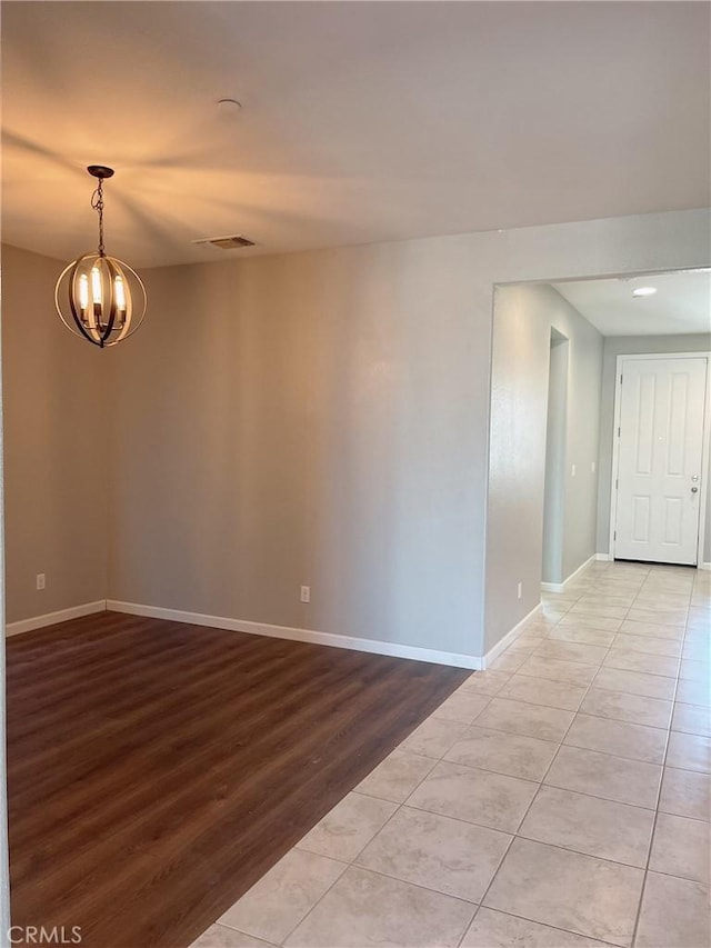 spare room with light wood-type flooring and a chandelier