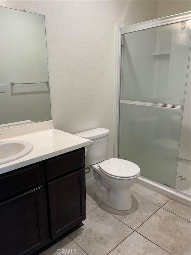 bathroom featuring toilet, vanity, tile patterned floors, and walk in shower