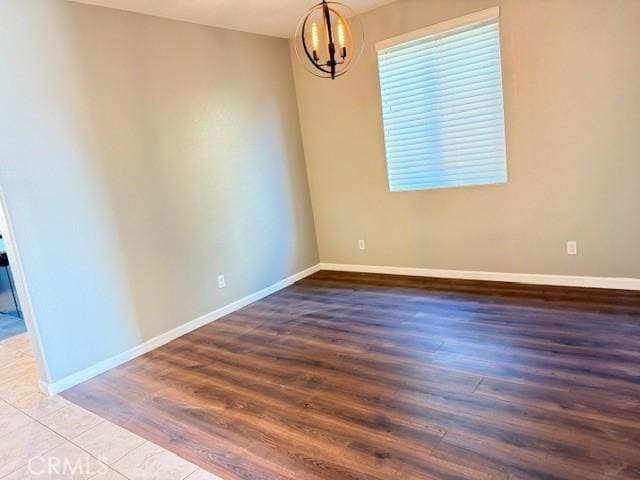 empty room featuring hardwood / wood-style floors and an inviting chandelier