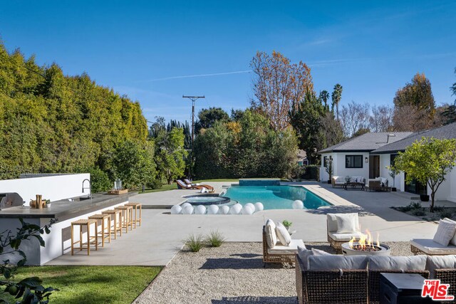 view of swimming pool with an outdoor fire pit, a bar, and a patio area