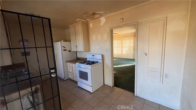 kitchen with light tile patterned flooring, white appliances, and white cabinetry