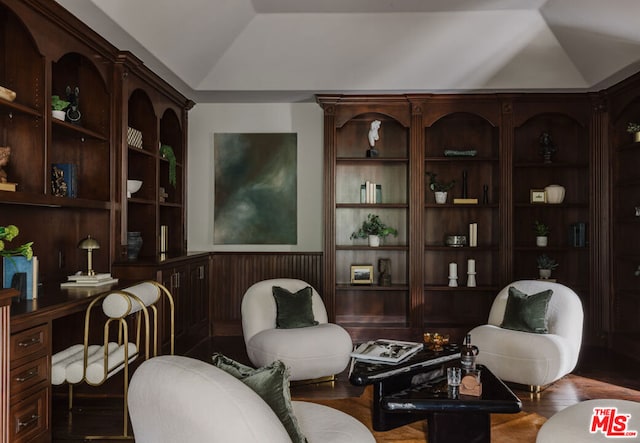 sitting room with lofted ceiling, built in features, wood-type flooring, and wooden walls