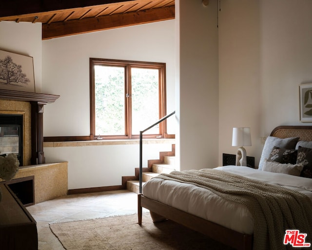 bedroom featuring wooden ceiling, a fireplace, and lofted ceiling with beams