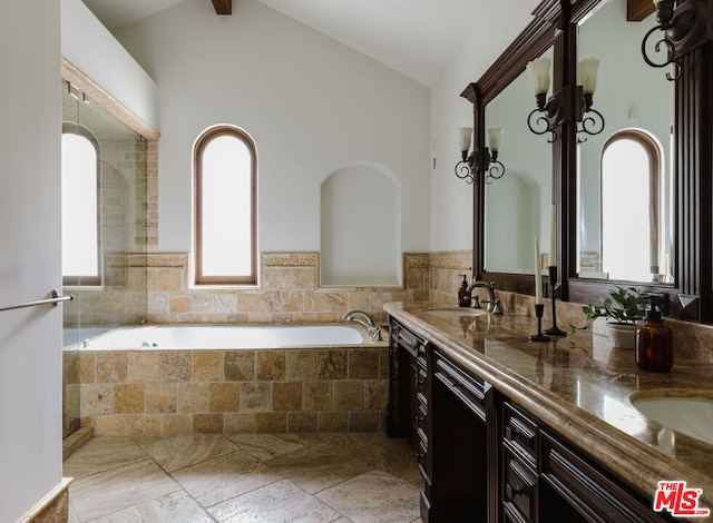 bathroom featuring beam ceiling, vanity, a wealth of natural light, and a relaxing tiled tub