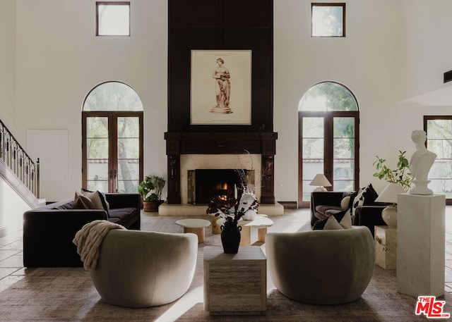 living room with a high ceiling, a fireplace, and french doors