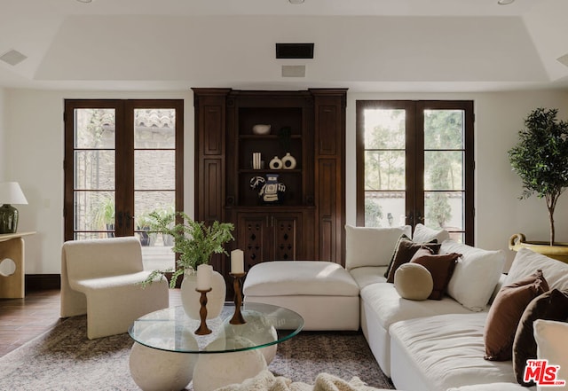 living room featuring french doors, a tray ceiling, and wood-type flooring